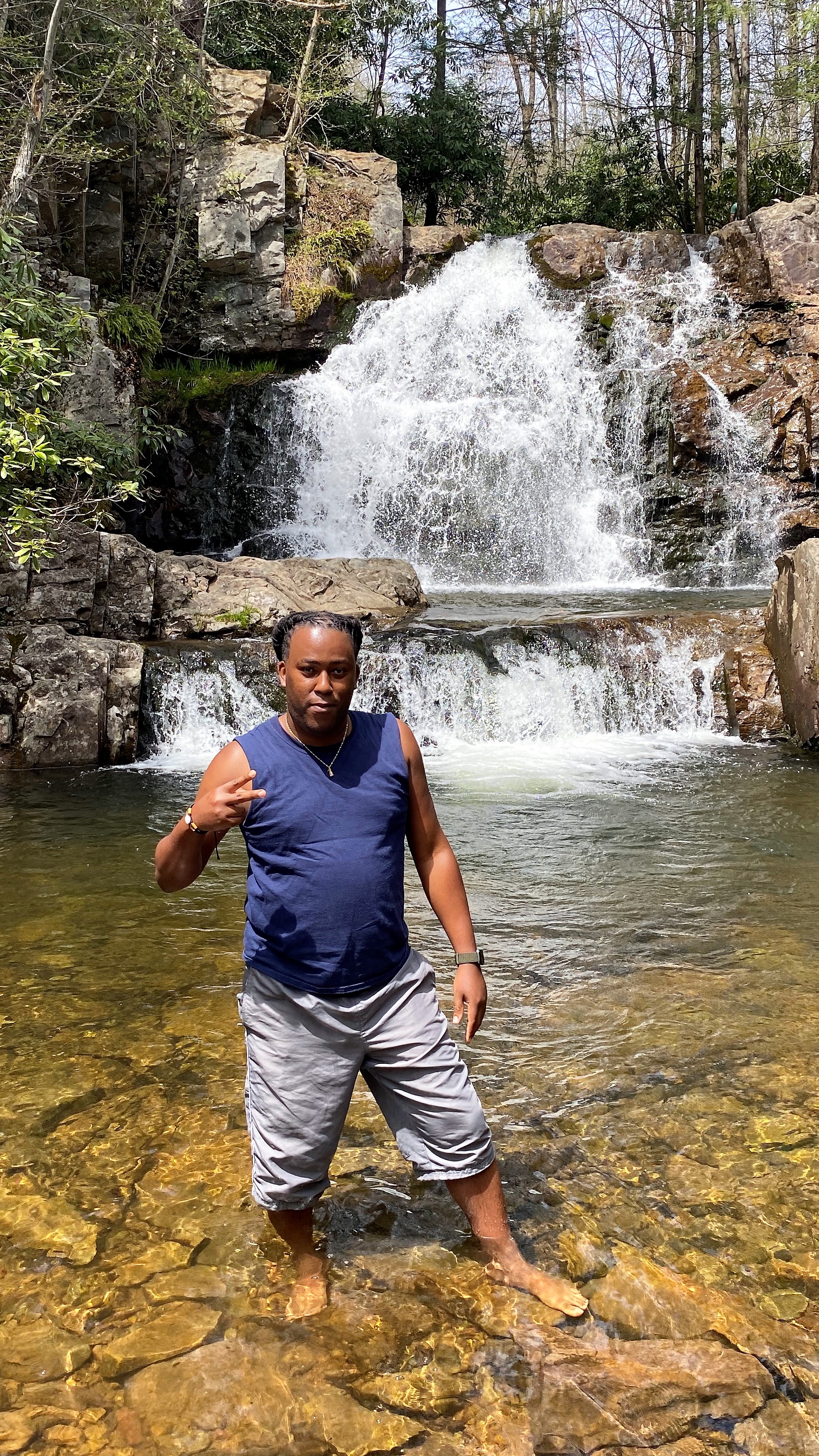 A handsome visitor throwing up the peace sign in front of Hawk Falls.
